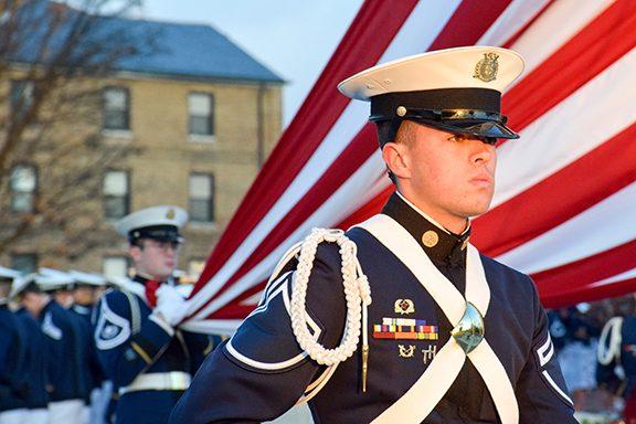A cadet stands in front of an American flag.